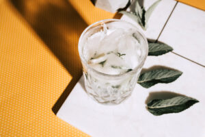 Mojito alcoholic cocktail with lime, mint and ice in a crystal glass shot with hard lights on yellow dots background and marble. Vintage edit and feel